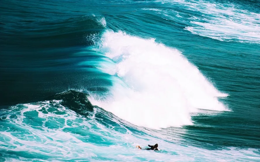 A surfer paddling out beneath a heaving set near Sydney
