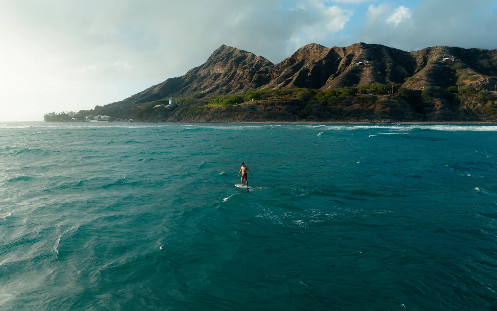 A rider in the Waikiki lineup with Diamond Head behind