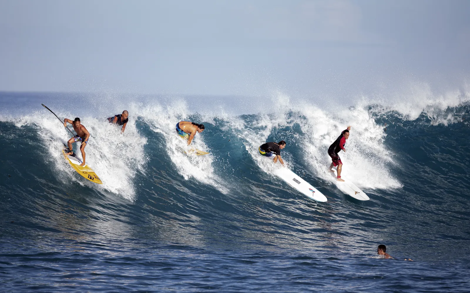 Four surfers dropping into the same wave at Paea, Tahiti